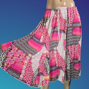 May include: A knee-length skirt featuring a vibrant patchwork design with various patterns including leopard print, pink circles, and wavy lines. The skirt has a white drawstring waistband and a flared silhouette with a scalloped hemline.