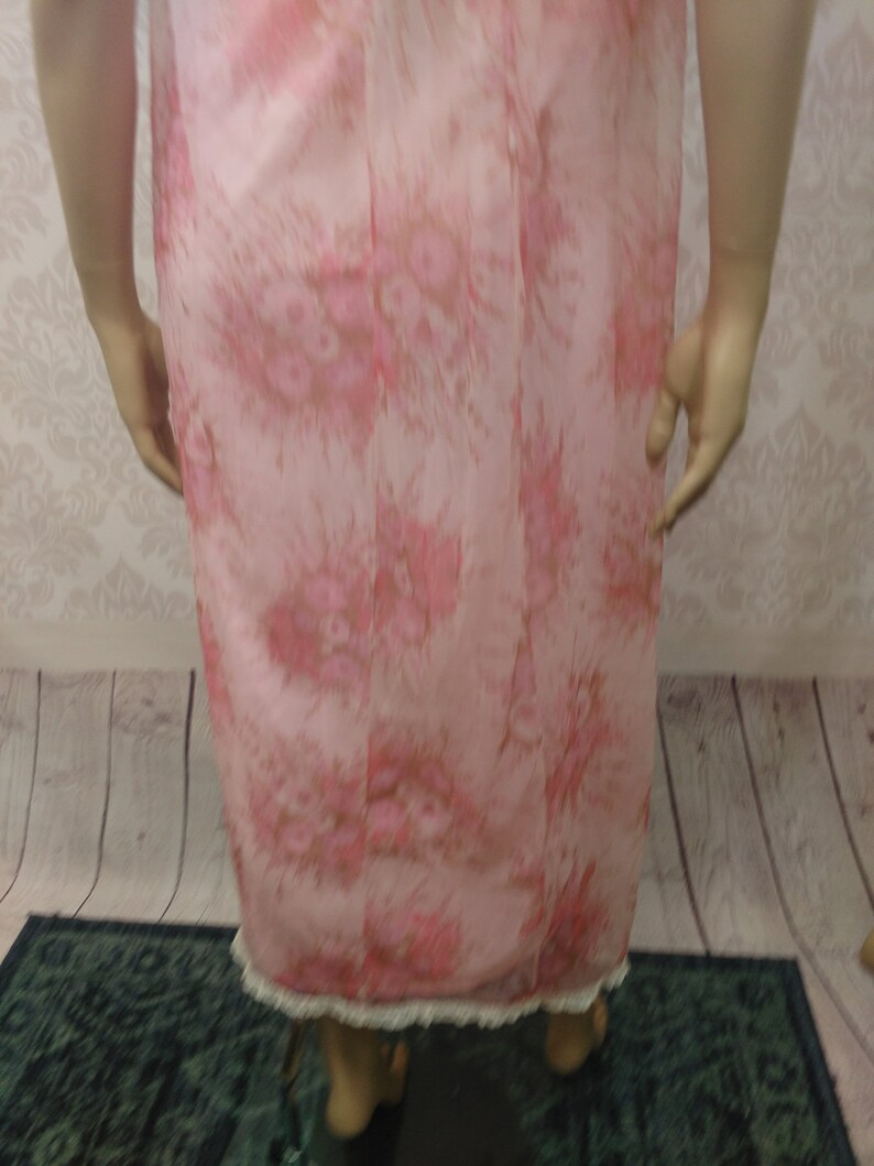 Pode incluir: Camisola vintage com estampa floral rosa. A camisola apresenta um delicado padr&atilde;o floral em tons de rosa e castanho. A bainha &eacute; adornada com renda branca. A camisola &eacute; exibida em um manequim.