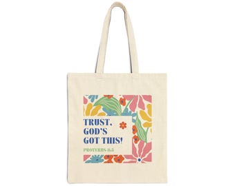 May include: Cream tote bag featuring the text "TRUST. GOD'S GOT THIS!" and "PROVERBS 3:5" within a square floral design. The design incorporates pink, blue, yellow, and green flowers and leaves. The bag has two handles.