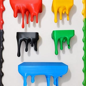 May include: A rectangular wall-mounted frame featuring a multi-colored border with a dripping paint effect. Inside the frame are five individual shelves in red, yellow, black, green, and blue, each designed with a realistic dripping paint aesthetic.