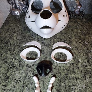 May include: A white 3D printed animal mask base featuring large eye sockets, a nose opening, and a mouth area. Included are two separate white brow pieces, two white eye rims, a black nose piece, and a white set of teeth for assembly.