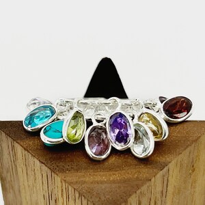 May include: A silver charm bracelet with a variety of colorful gemstone charms, including turquoise, amethyst, peridot, and garnet.