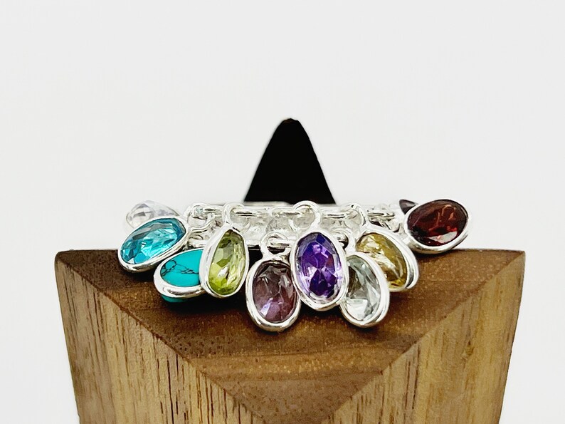 May include: A silver charm bracelet with a variety of colorful gemstone charms, including turquoise, amethyst, peridot, and garnet.