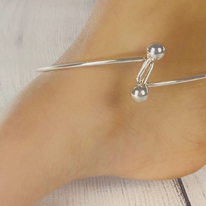 May include: Silver ankle bracelet with two round balls on the clasp.