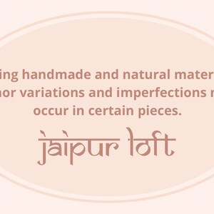 May include: A light pink oval with a white outline. The text "Being handmade and natural material minor variations and imperfections may occur in certain pieces." is written in brown text. The text "jaipur loft" is written in brown text in a decorative font.