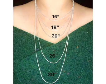 May include: Five silver chains of different lengths, 16 inches, 18 inches, 20 inches, 26 inches, and 30 inches, are shown on a person's neck.