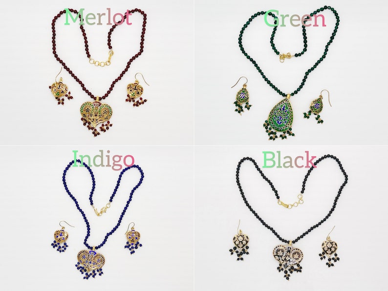 May include: Four sets of jewelry featuring a necklace and earrings. Each set has a different colored bead necklace and a pendant with a heart or teardrop shape. The pendants are decorated with intricate designs and colorful enamel. The colors of the necklaces are merlot, green, indigo, and black.