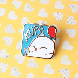 May include: A gold-coloured enamel pin featuring a cartoon white character with a red balloon. The character has a blue background with the word "KUPO" written in gold letters.