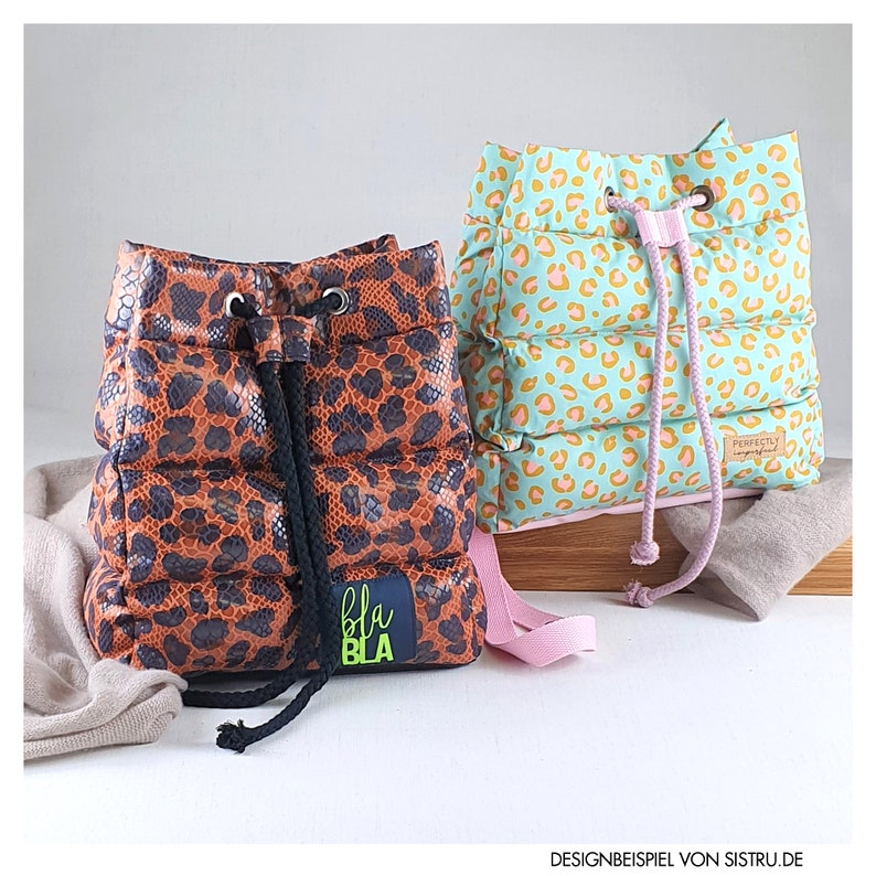 May include: Two drawstring backpacks. One is brown with a leopard print and a black drawstring. The other is mint green with a leopard print and a pink drawstring. The brown bag has a blue patch with the text "bla bla".