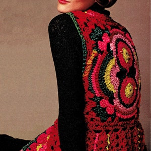 以下が含まれることがあります： 赤、緑、黄、ピンクのクロシェ編みのベストで、花柄のデザインが施されています。ベストは黒い長袖シャツの上に着用されています。ベストには「Twine Warp」という文字が見えます。