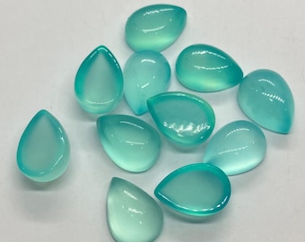 May include: Ten teal blue teardrop shaped cabochons, each with a smooth, polished surface.
