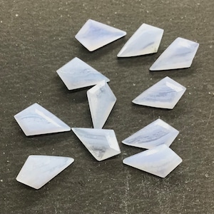 Op de afbeelding: Een verzameling van tien lichtblauwe agaat edelsteen cabochons gesneden in een vlieger vorm. De cabochons zijn glad en gepolijst, met een doorschijnende uitstraling.