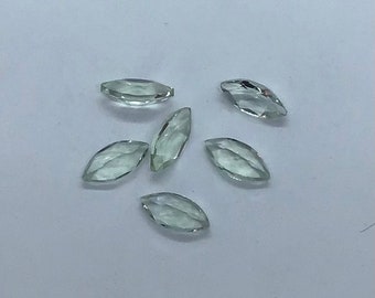 May include: Six light green marquise-shaped gemstones, also known as emerald cut, on a white background.