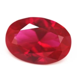 May include: A deep red oval-shaped ruby gemstone with a faceted cut.