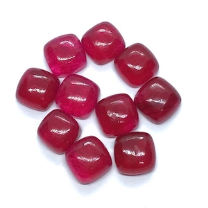 Könnte beinhalten: Zehn leuchtend rosa quadratische Edelsteine. Die Edelsteine sind glatt und poliert.