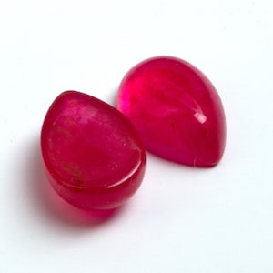 以下が含まれることがあります： 涙の形をした、明るいピンクの宝石が2つ。宝石は滑らかで磨かれています。