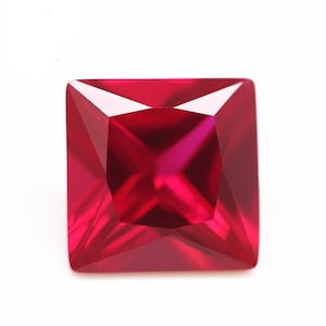 May include: A deep red square-shaped gemstone with a faceted cut.