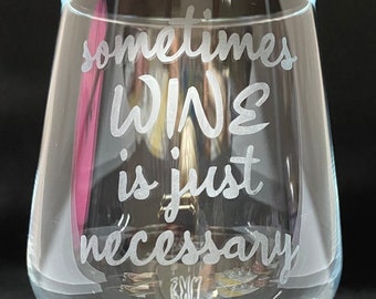 May include: A clear glass wine glass with the text "sometimes wine is just necessary" etched on the side.
