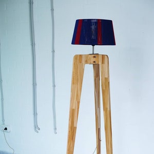 May include: A floor lamp with a wooden tripod stand and a blue and red striped lampshade.