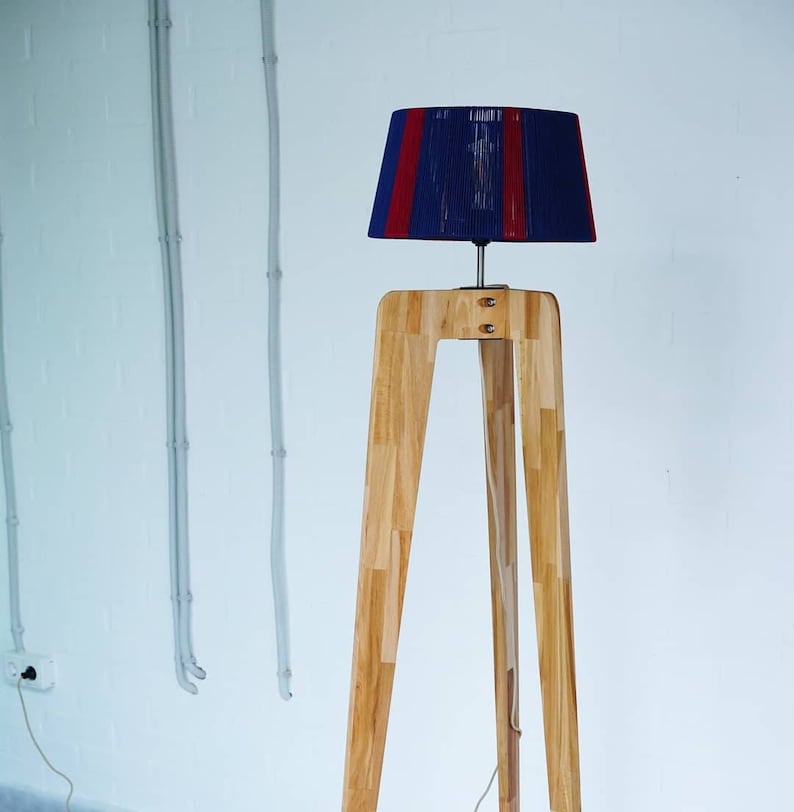 May include: A floor lamp with a wooden tripod stand and a blue and red striped lampshade.