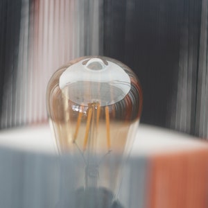 May include: A close-up of a clear glass light bulb with a warm, golden glow. The filament is visible inside the bulb.