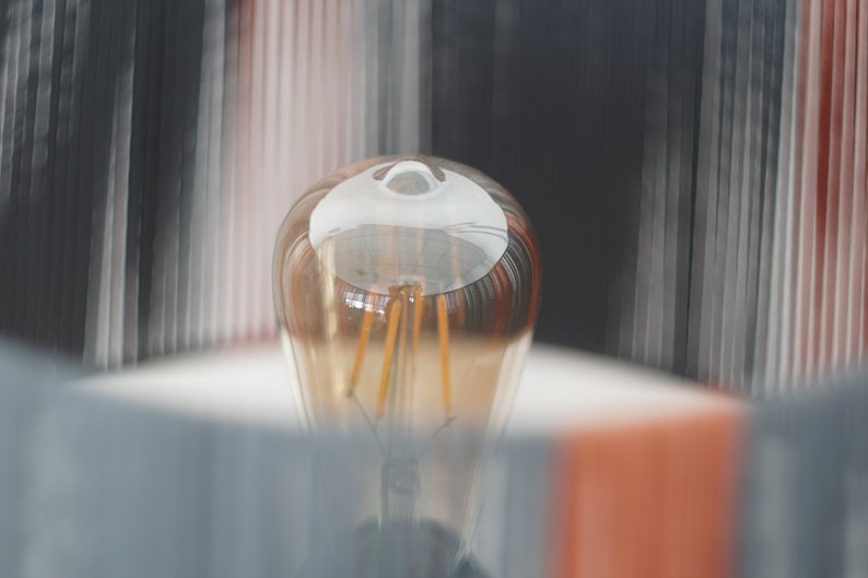 May include: A close-up of a clear glass light bulb with a warm, golden glow. The filament is visible inside the bulb.