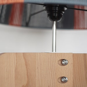 May include: A wooden lamp base with a gray and orange lampshade. The lampshade is attached to the base with a metal rod and screws. The lampshade has a striped pattern.