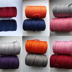 May include: Assortment of spools of colorful cord in various colors including red, orange, navy blue, gray, pink, and purple. The cords are wound around spools and are ready to be used for crafting projects.
