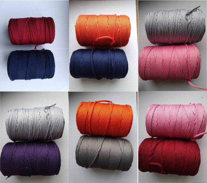 May include: Assortment of spools of colorful cord in various colors including red, orange, navy blue, gray, pink, and purple. The cords are wound around spools and are ready to be used for crafting projects.