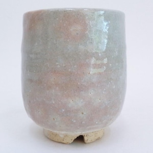 May include: A small, light gray ceramic cup with a pink and white glaze. The cup has a rounded bottom and a slightly flared rim.