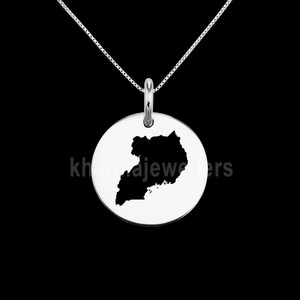 May include: A silver necklace with a round pendant featuring a black silhouette of the map of Uganda.