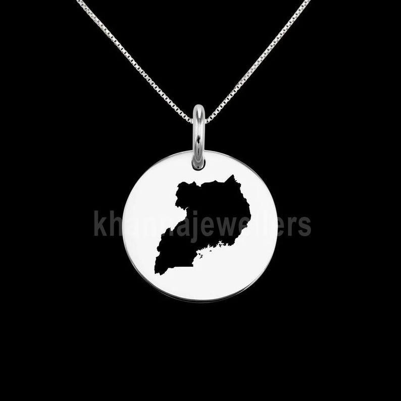 May include: A silver necklace with a round pendant featuring a black silhouette of the map of Uganda.