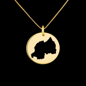 Può includere: Una collana d'oro con un ciondolo rotondo che presenta un'incisione a forma di contorno del Ruanda. Il ciondolo è sospeso da una delicata catena d'oro.