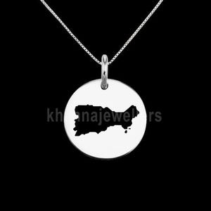 Puede incluir: Un collar de plata con un colgante redondo que presenta una silueta negra de la isla de Puerto Rico.