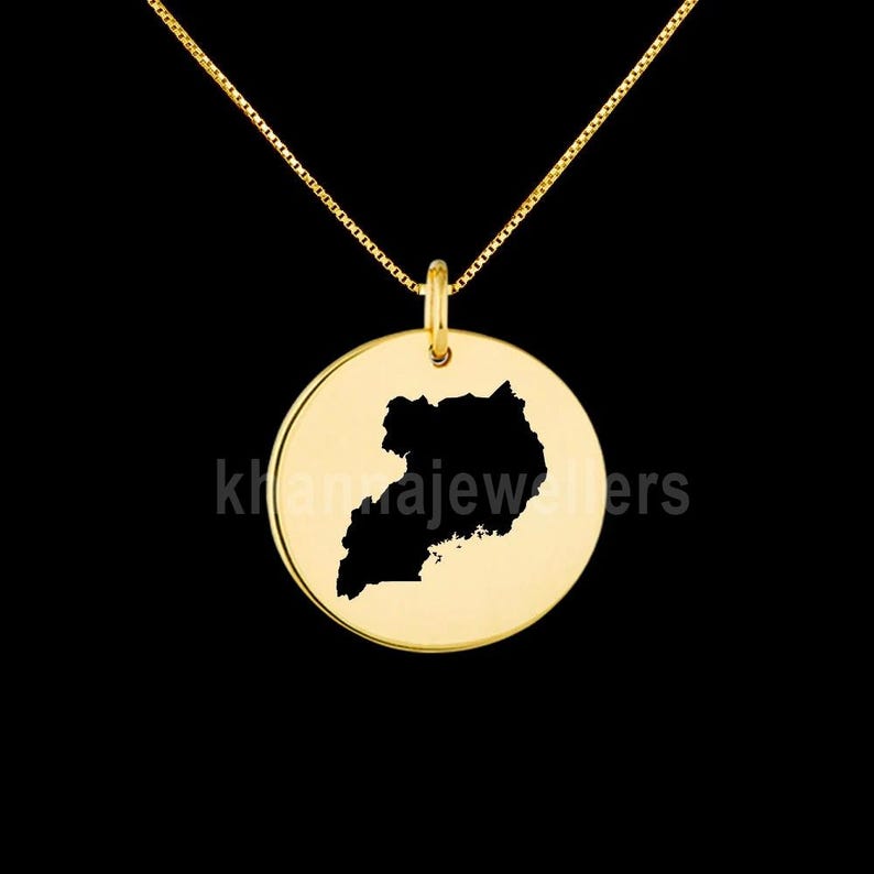 May include: A gold necklace with a round pendant featuring a black silhouette of the map of Uganda.