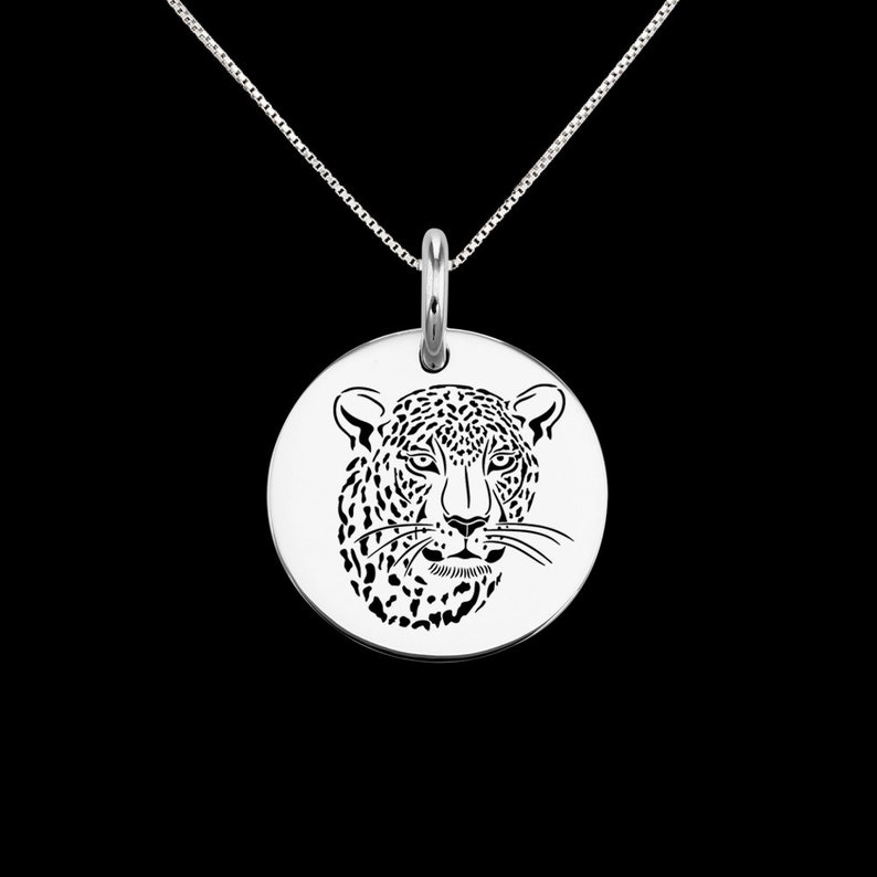 May include: A silver necklace with a round pendant featuring a detailed cutout design of a leopard's face.