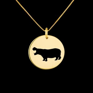 May include: Gold necklace with a round pendant featuring a black silhouette of a hippopotamus.