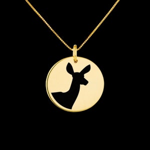 May include: A gold necklace with a round pendant featuring a silhouette of a deer head.