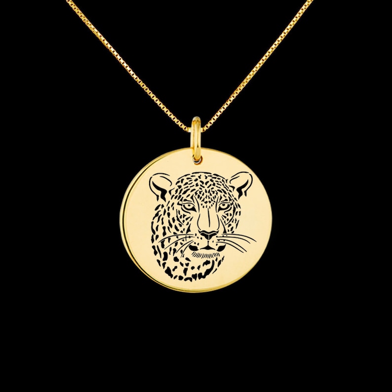 May include: A gold necklace with a round pendant featuring a detailed silhouette of a leopard's face.