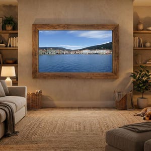 Könnte beinhalten: Ein gemütliches Wohnzimmer mit einem großen gerahmten Bild einer Meereslandschaft. Der Raum verfügt über ein Sofa, einen Kamin und Bücherregale. Ein Hund liegt auf dem Boden. Der Raum wird von Lampen und natürlichem Licht beleuchtet, was eine warme Atmosphäre schafft.