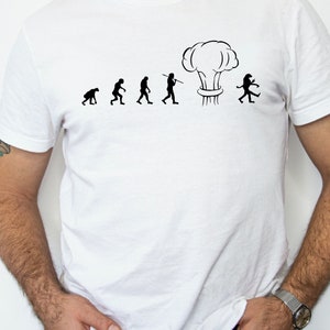 May include: A white t-shirt with a black graphic of the evolution of humans ending with a mushroom cloud.