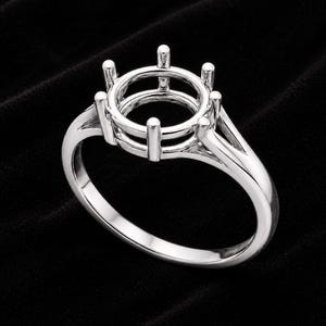 May include: A polished silver-toned metal ring setting featuring a six-prong head designed to hold a single round gemstone. The band has a split-shank design that tapers toward the base, creating a clean, structural frame for a future stone setting.