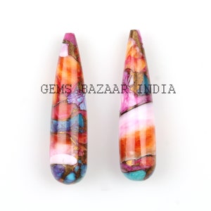 May include: Two teardrop-shaped gemstone pendants. The pendants feature a mix of colors including pink, orange, teal, and gold. The text "GEMS BAZAAR INDIA" is printed on the image.
