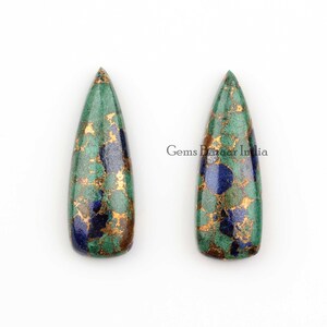 Könnte beinhalten: Zwei tropfenförmige grüne, goldene und blaue Edelsteinkabochons. Gems Bazaar India.