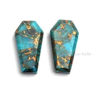 May include: Two turquoise and gold gemstone cabochons in a coffin shape.
