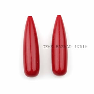 May include: Two red coral teardrop shaped beads. The beads are smooth and polished.