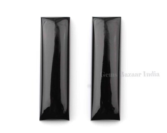 May include: Two black rectangular cabochons, likely made of onyx or jet, with a polished finish. The stones are approximately 1 inch long and 1/4 inch wide.