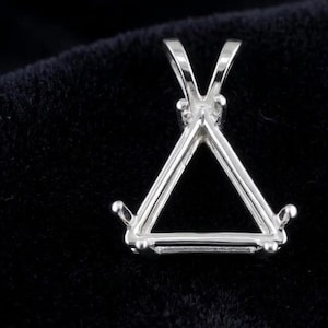 May include: A silver-toned metal pendant setting featuring a triangular frame designed to hold a gemstone. The setting includes three prongs at the corners and a V-shaped bail at the top for attaching to a chain, showcasing a polished metallic finish.
