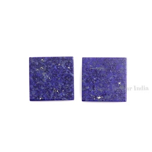 May include: Two square pieces of lapis lazuli gemstone. The stones are a deep blue color with flecks of gold pyrite.