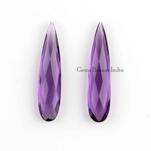 May include: Two purple amethyst teardrop shaped gemstone beads. The beads are faceted and have a pointed tip.